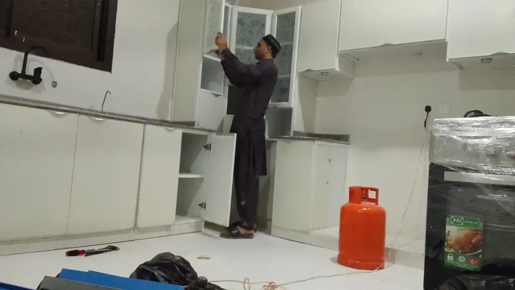 فني متخصص يفحص ويصلح مفصلات باب خزانة مطبخ ألمنيوم بالرياض