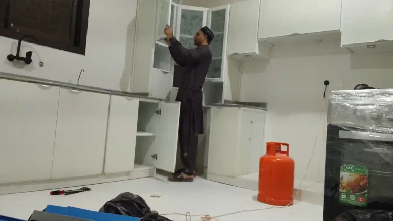 فني متخصص يفحص ويصلح مفصلات باب خزانة مطبخ ألمنيوم بالرياض